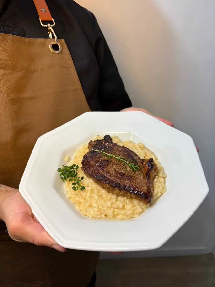 Prato de bife grelhado sobre risoto, servido pela Chef Waléria
