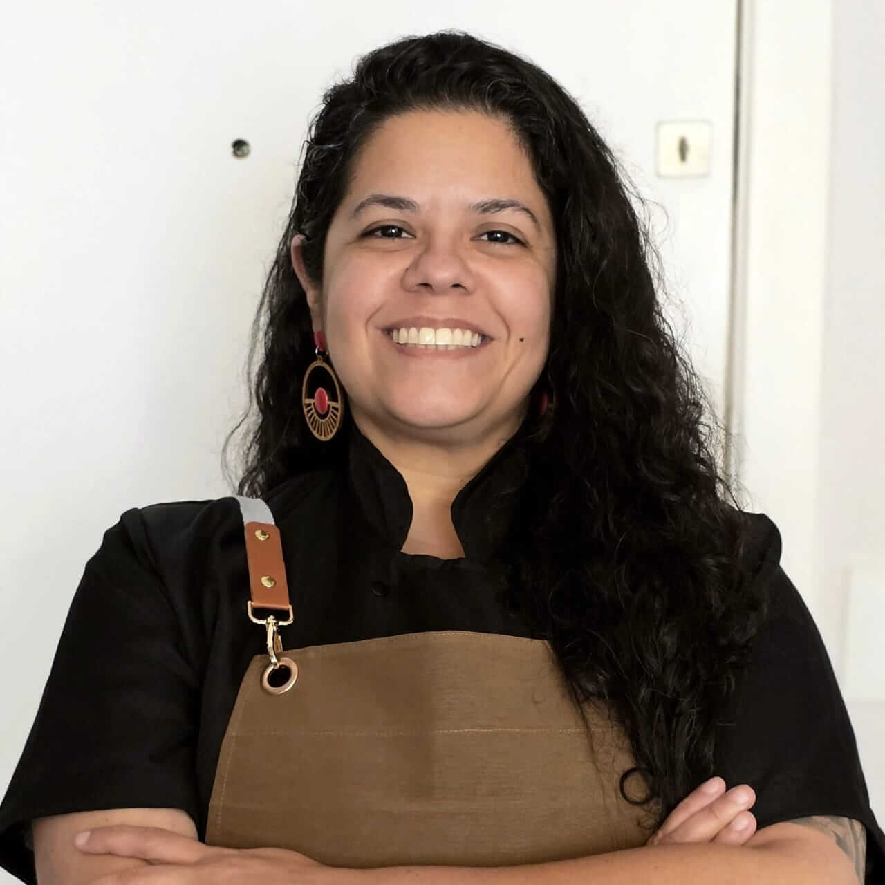 Chef Waléria Marques sorrindo, vestida com dólmã e avental