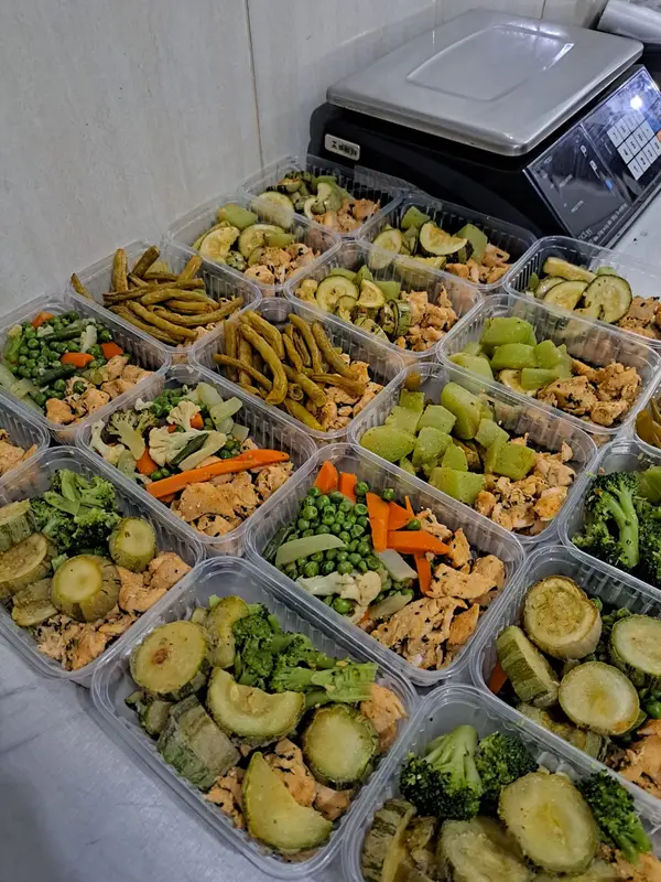 Porções de frango com vagem, abobrinha, chuchu e couve-flor organizadas em potes